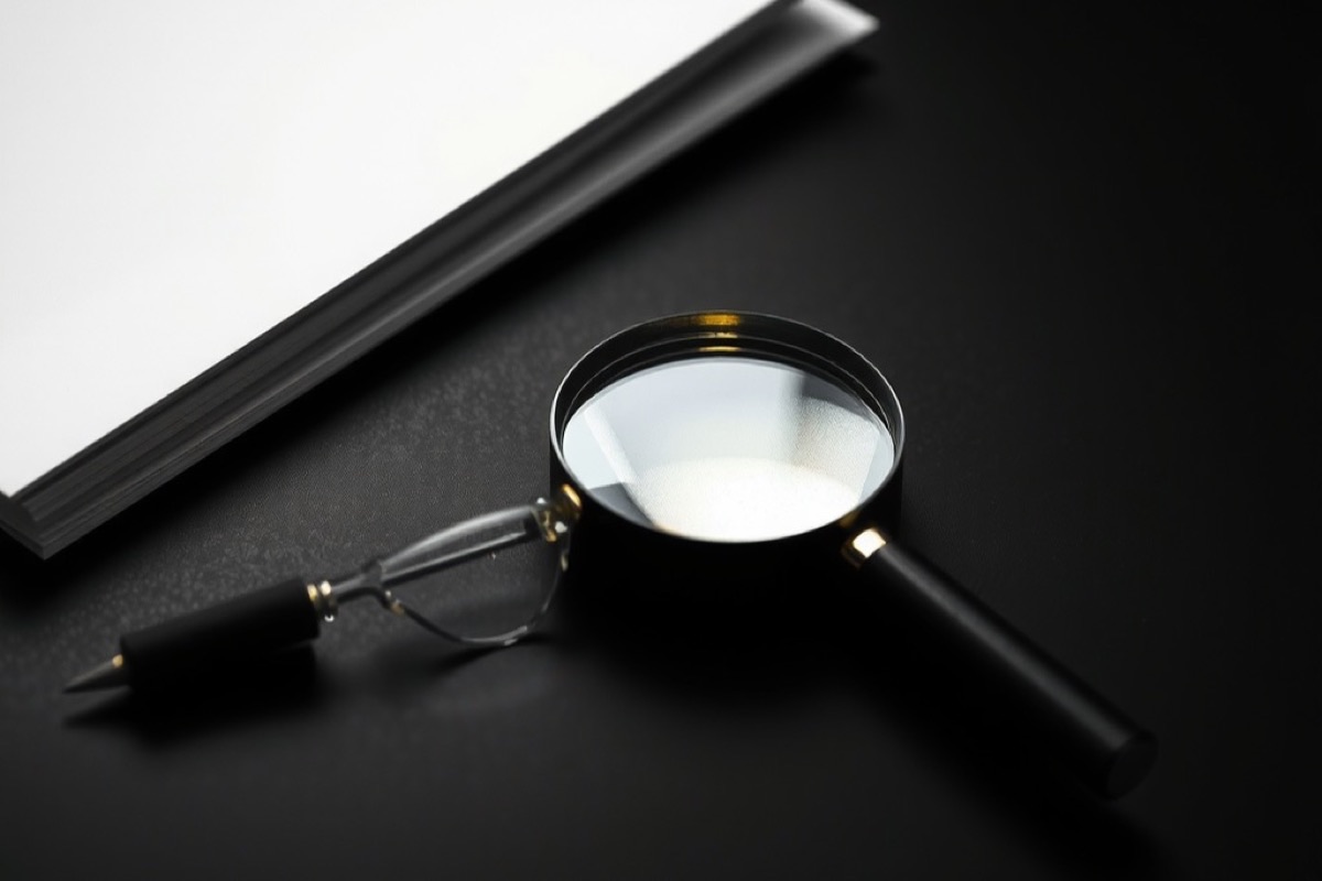 A magnifying glass lying on a desk beside a closed folder