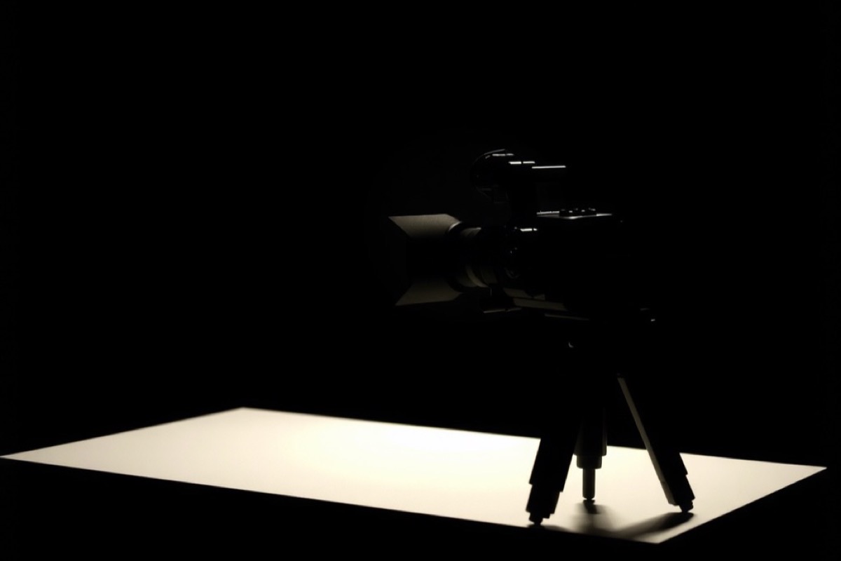 A card table in a dark studio with a broadcast camera pointed at it