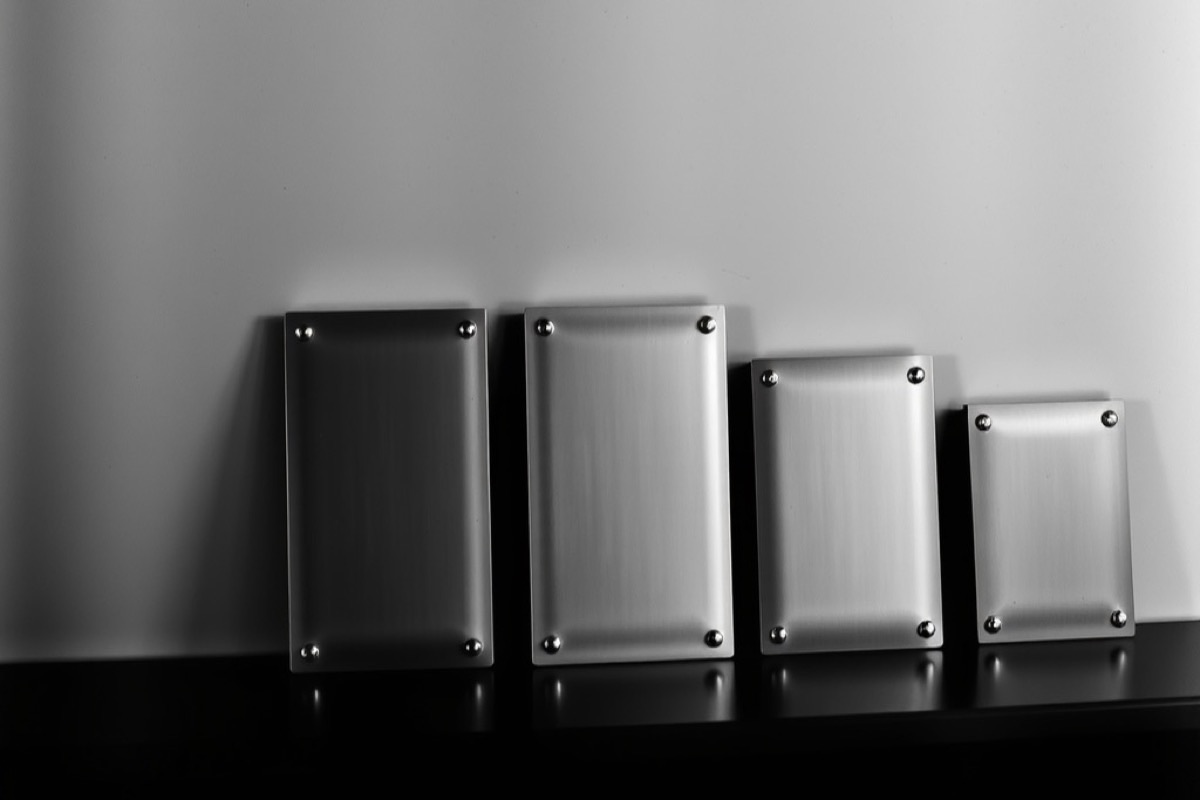 Five metal plaques in ascending sizes standing on a dark shelf